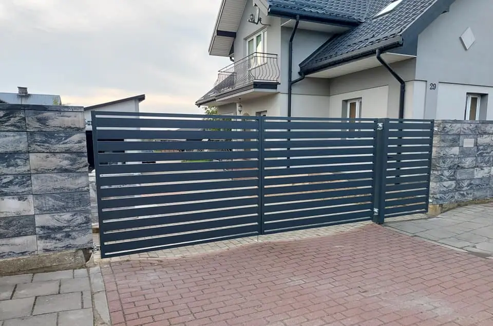 Brama przesuwna palisadowa przy kamiennych słupkach