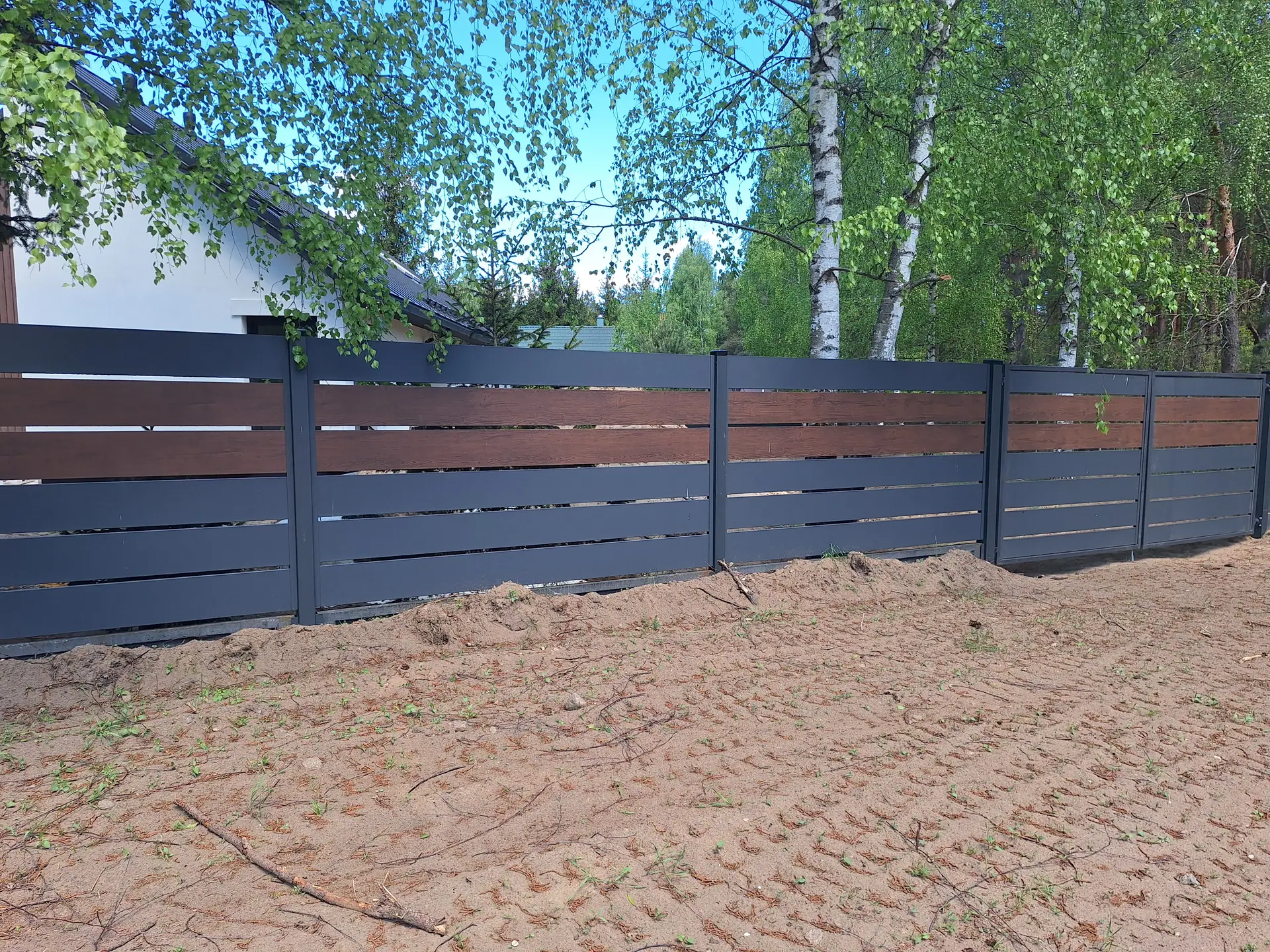 Palisada w kolorze antracytu z akcentem w kolorze drewna wzdłuż działki